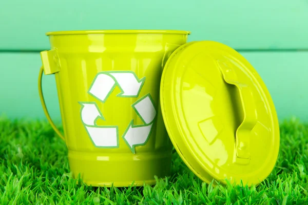 Recycling-Tonne auf grünem Gras auf hölzernem Hintergrund — Stockfoto