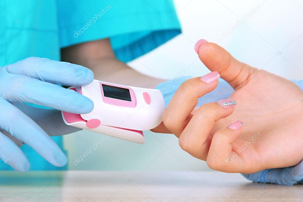Doctor measuring pulse rate and oxygen levels, on bright background