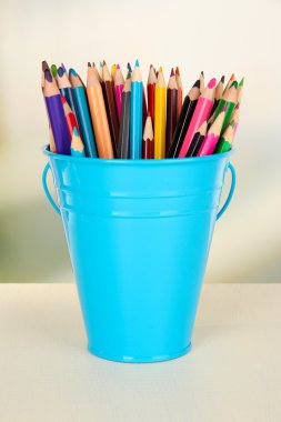 renk renk arka plan üzerinde renkli kalemler ile kova