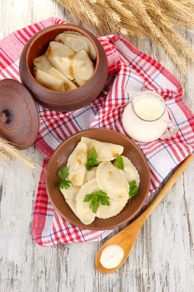 Tasty dumplings with fried onion on brown plate, on wooden background — Stock Photo, Image