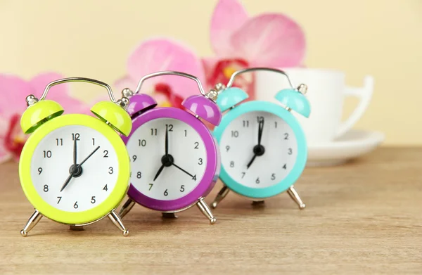 Reloj despertador colorido en la mesa sobre fondo beige — Foto de Stock