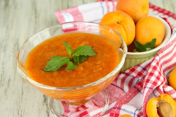 Apricot jam in glass bowl and fresh apricots, on wooden background — Stock Photo, Image