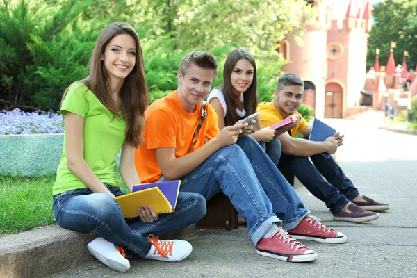 Šťastný skupina mladých studentů, sedět v parku — Stock fotografie