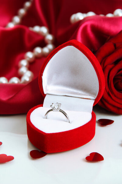 Beautiful box with wedding ring and rose on red silk background