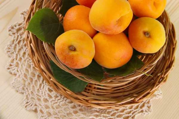 Apricots on wicker coasters on napkin on wooden table — Stock Photo, Image