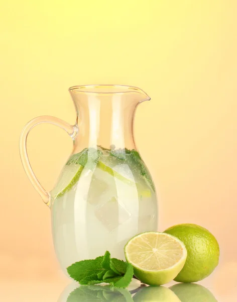 Lemonade in pitcher on yellow background — Stock Photo, Image