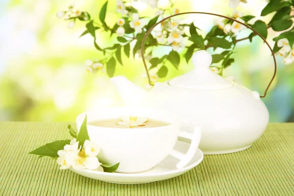 Taza de té con jazmín, sobre estera de bambú, sobre fondo brillante —  Fotos de Stock