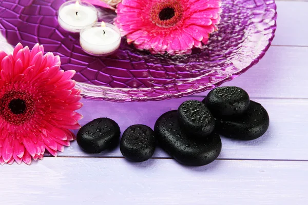 Wellness-Steine, schöne Gerbera-Blumen und Kerzen auf dem Wasser — Stockfoto