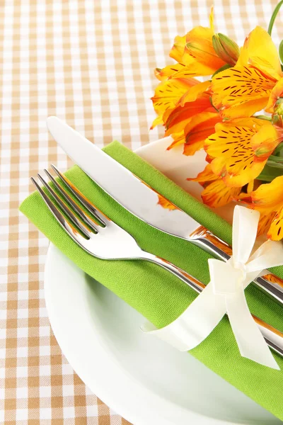 Накрытие праздничного обеденного стола с цветами на клетчатом фоне — стоковое фото