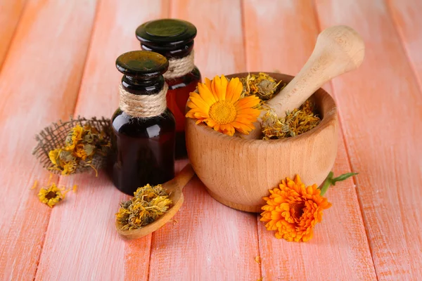 Bottiglie di medicina e fiori di calendula su sfondo di legno — Foto Stock