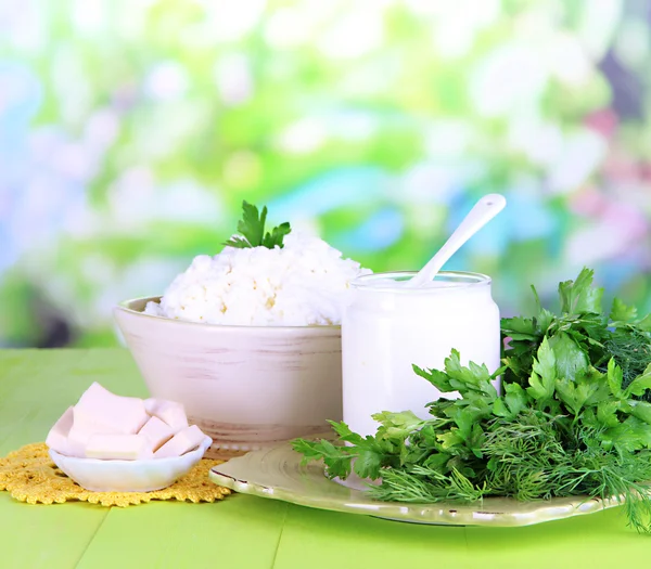 Fresh dairy products with greens on wooden table on natural background — Stock Photo, Image