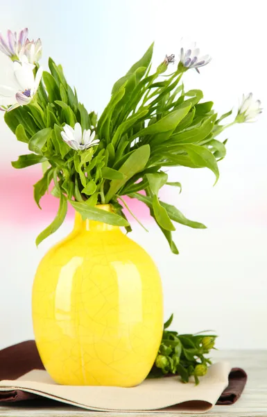 Buquê de belas flores de verão em vaso de cor, na mesa de madeira, no fundo brilhante — Fotografia de Stock