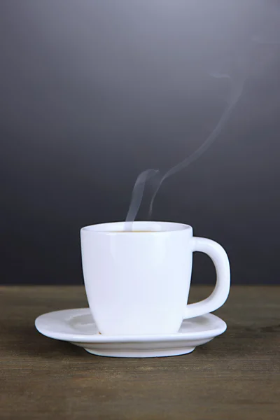 Taza de café sobre mesa de madera sobre fondo negro —  Fotos de Stock