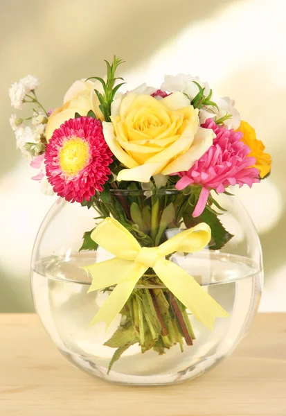Vacker bukett av ljusa blommor i vas, på träbord, på ljus bakgrund — Stockfoto