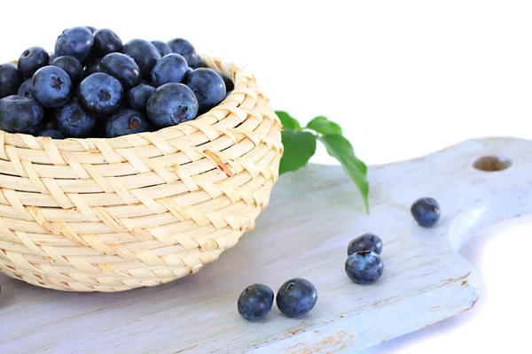 Blueberries in wooden basket on wooden board isolated on white — Stock Photo, Image