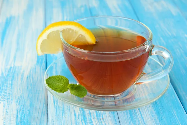 Taza de té con limón sobre la mesa sobre fondo azul —  Fotos de Stock