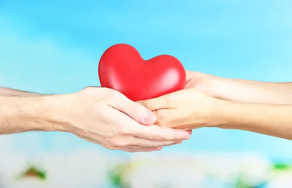 Corazón en manos sobre fondo nublado — Foto de Stock