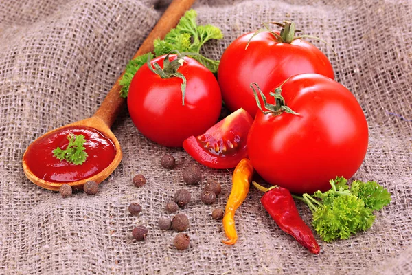 Ketchup and ripe tomatoes on sacking close-up — Stock Photo, Image