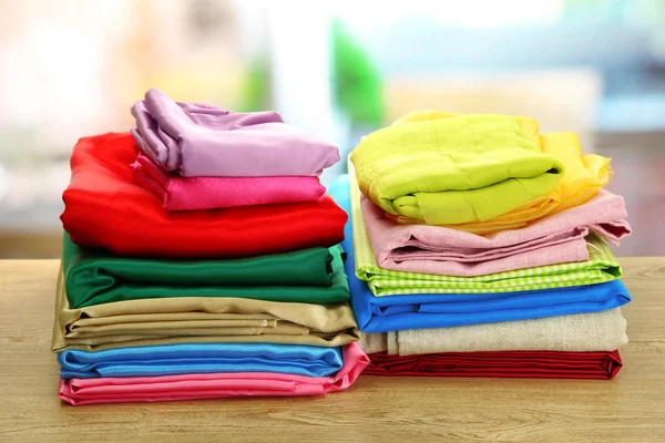 Heap of cloth fabrics on wooden table — Stock Photo, Image