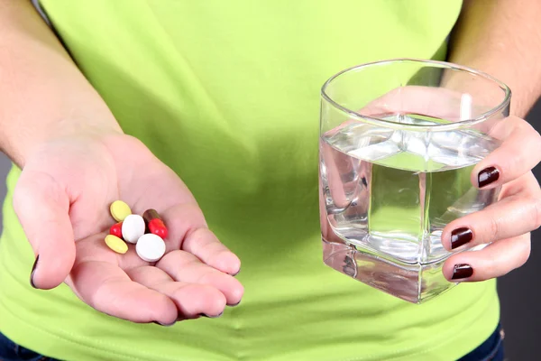 Beaucoup de pilules et d'eau en verre à la main — Photo