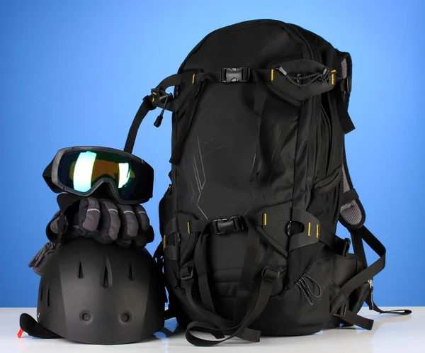 Wintersportbrille, Helm und Handschuhe, Rucksack, auf blauem Hintergrund — Stockfoto