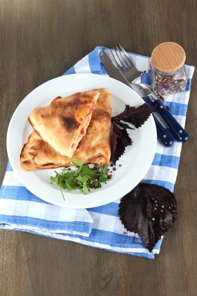 Pizza Calzone na štítku na ubrousek na dřevěný stůl — Stock fotografie