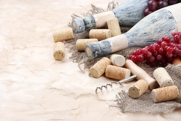 Old bottles of wine, grapes and corks on old paper background — Stock Photo, Image