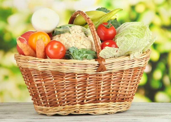 Verduras frescas en cesta sobre mesa de madera sobre fondo natural — Foto de Stock