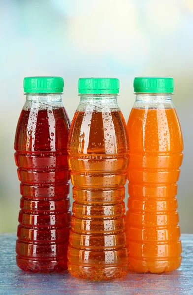 Assortment of bottles with tasty fruit juices on bright background — Stock Photo, Image