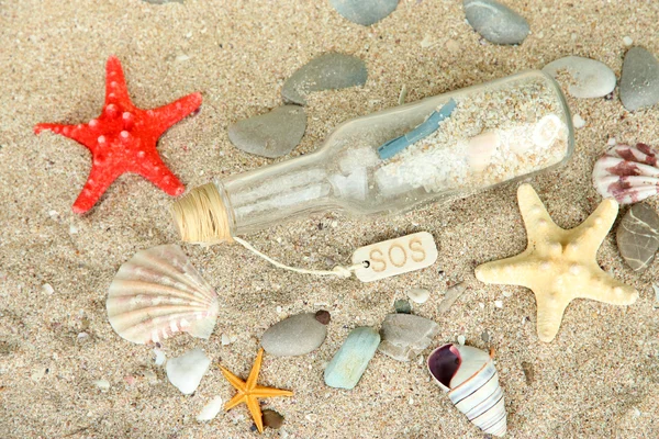 Verre de bouteille avec note à l'intérieur sur fond de sable — Photo