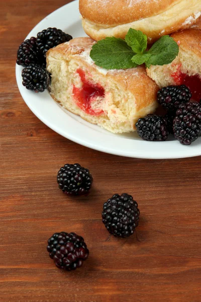 Smakelijke donuts met bessen op houten tafel — Stockfoto