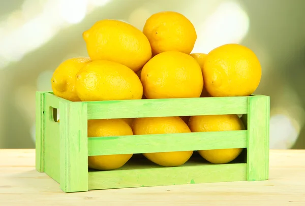 Limones maduros en caja de madera sobre mesa sobre fondo brillante —  Fotos de Stock