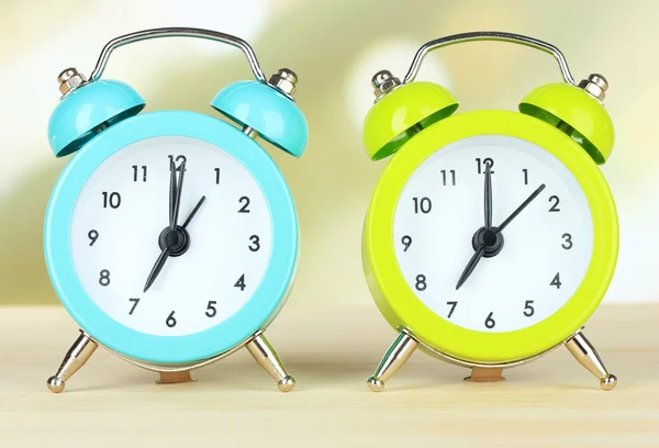 Colorful alarm clocks on table on light background — Stock Photo, Image