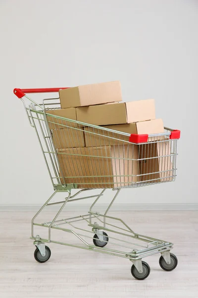 Shopping cart with carton, on gray background — Stock Photo, Image