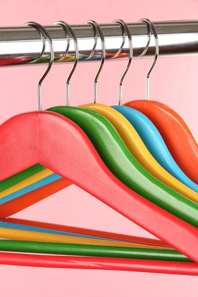 Kleurrijke kleerhangers op roze achtergrond — Stockfoto