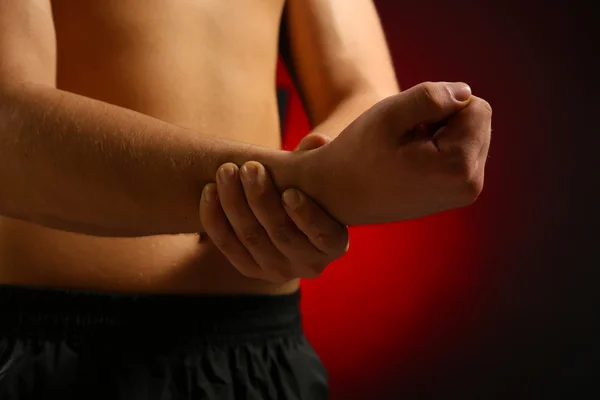 Junger Mann mit Schmerzen in der Hand, auf rotem Hintergrund — Stockfoto