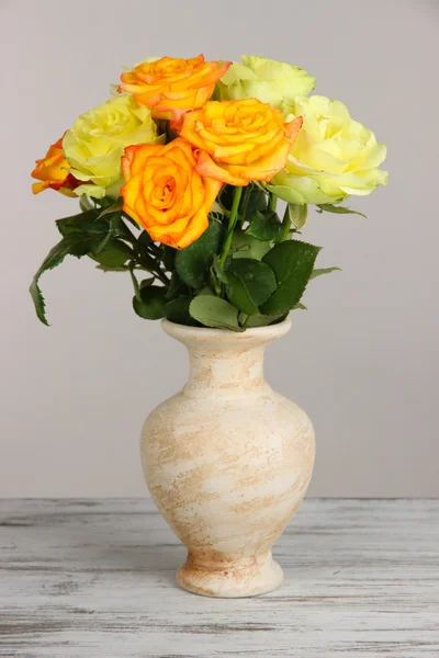 Beautiful bouquet of roses in vase on table on gray background — Stock Photo, Image