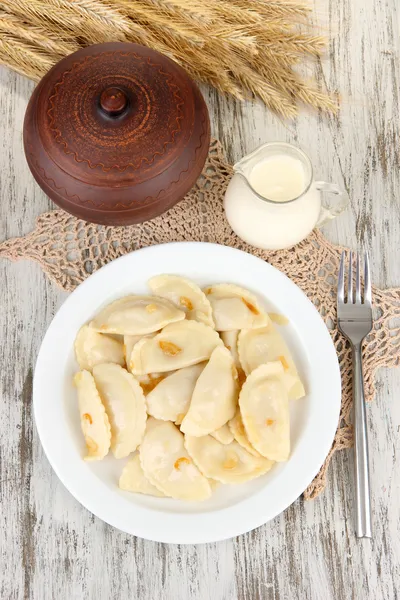 Tasty dumplings with fried onion on white plate, on wooden background — Stock Photo, Image