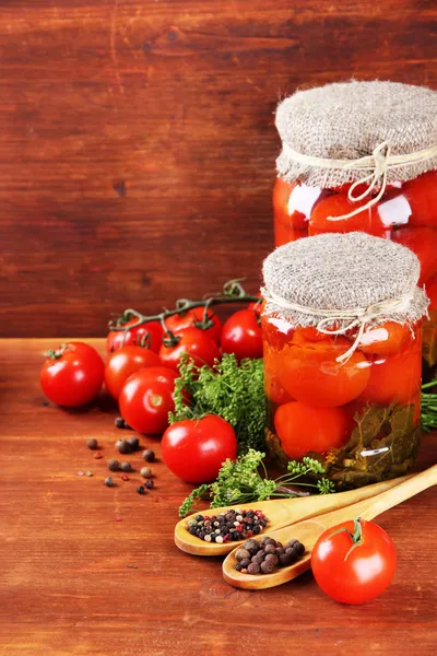 Smaczne konserwy i świeże pomidory na drewnianym stole — Zdjęcie stockowe