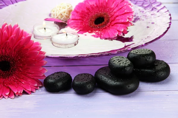 Pedras de spa, belas flores de gerbera e velas na água — Fotografia de Stock
