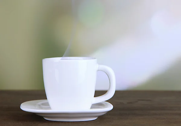 Cup of coffee on wooden table on bright background — Stock Photo, Image