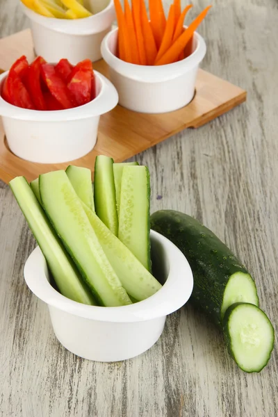 Ljusa färska grönsaker skära upp skivor i skålar på träbord närbild — Stockfoto
