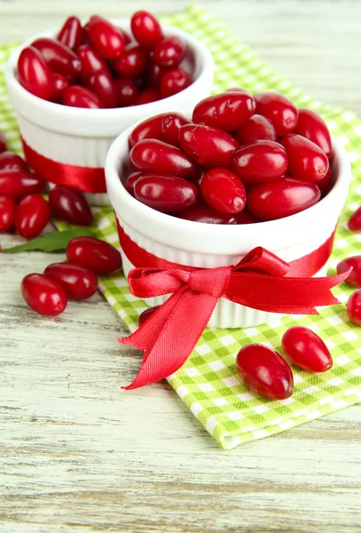 Fresh cornel berries in white cups on wooden table — Stock Photo, Image