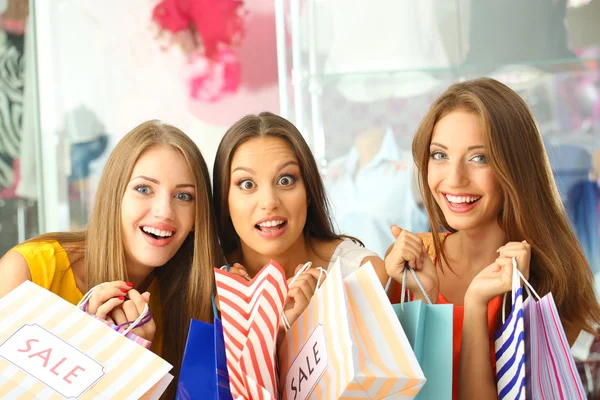 Three beautiful young woman in shop with shopping bags — Stock Photo, Image