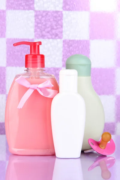 Cosméticos para bebés en el baño sobre fondo de pared de baldosas violeta —  Fotos de Stock