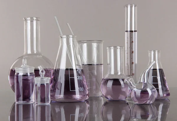 Test-tubes with light purple liquid on gray background — Stock Photo, Image