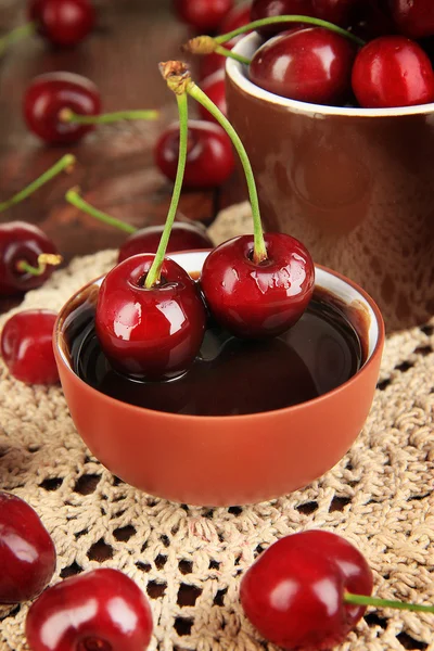 Bayas rojas maduras de cereza en taza y salsa de chocolate en primer plano de mesa de madera —  Fotos de Stock