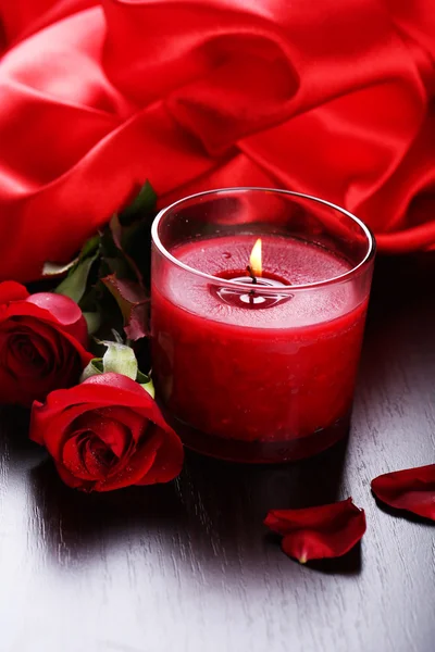 Hermosa vela roja romántica con flores y tela de seda, de cerca —  Fotos de Stock
