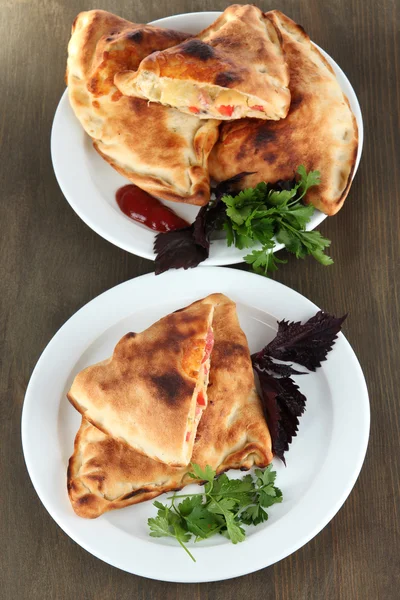 Pizza calzoni su piatti su tavola di legno — Foto Stock