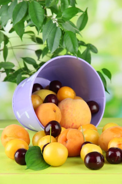 Frutas de verão brilhantes em balde na mesa de madeira no fundo natural — Fotografia de Stock